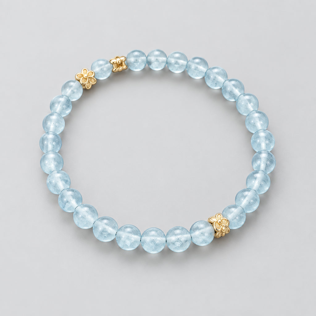 A beaded stretch bracelet made of light blue faceted round beads with two rose gold butterfly charms, displayed on a dark textured background.
