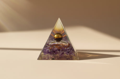 Pyramid-shaped crystal with a spherical object inside on a textured surface