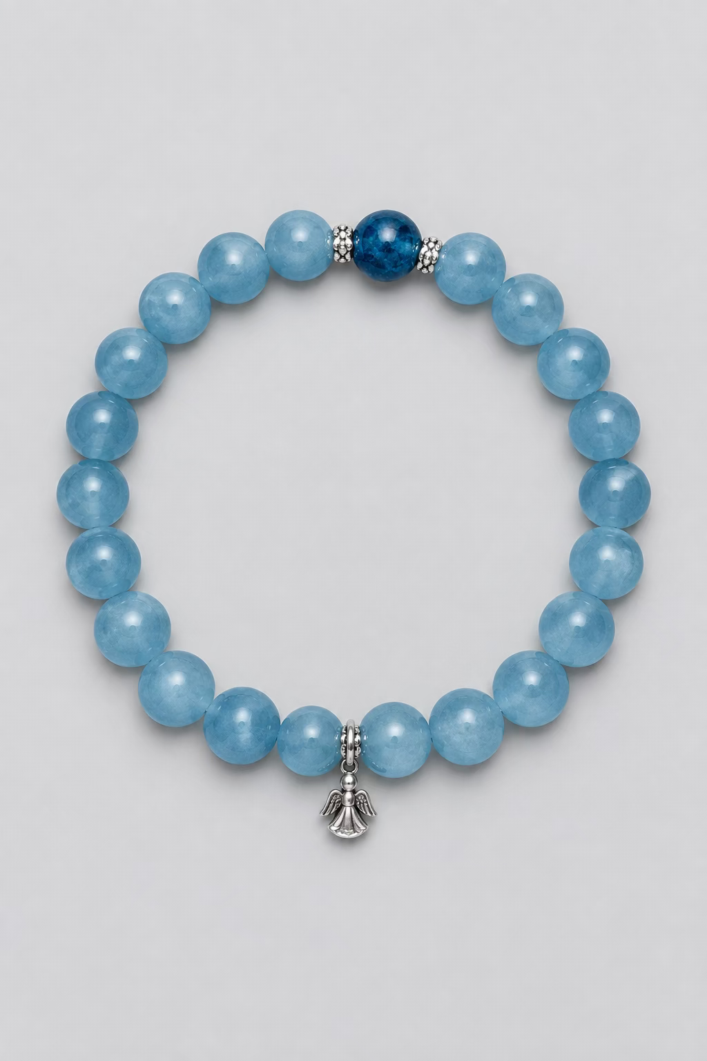 A beaded stretch bracelet made of light blue round beads, featuring one darker blue bead and a small silver-toned bell charm, displayed on a textured light gray background.