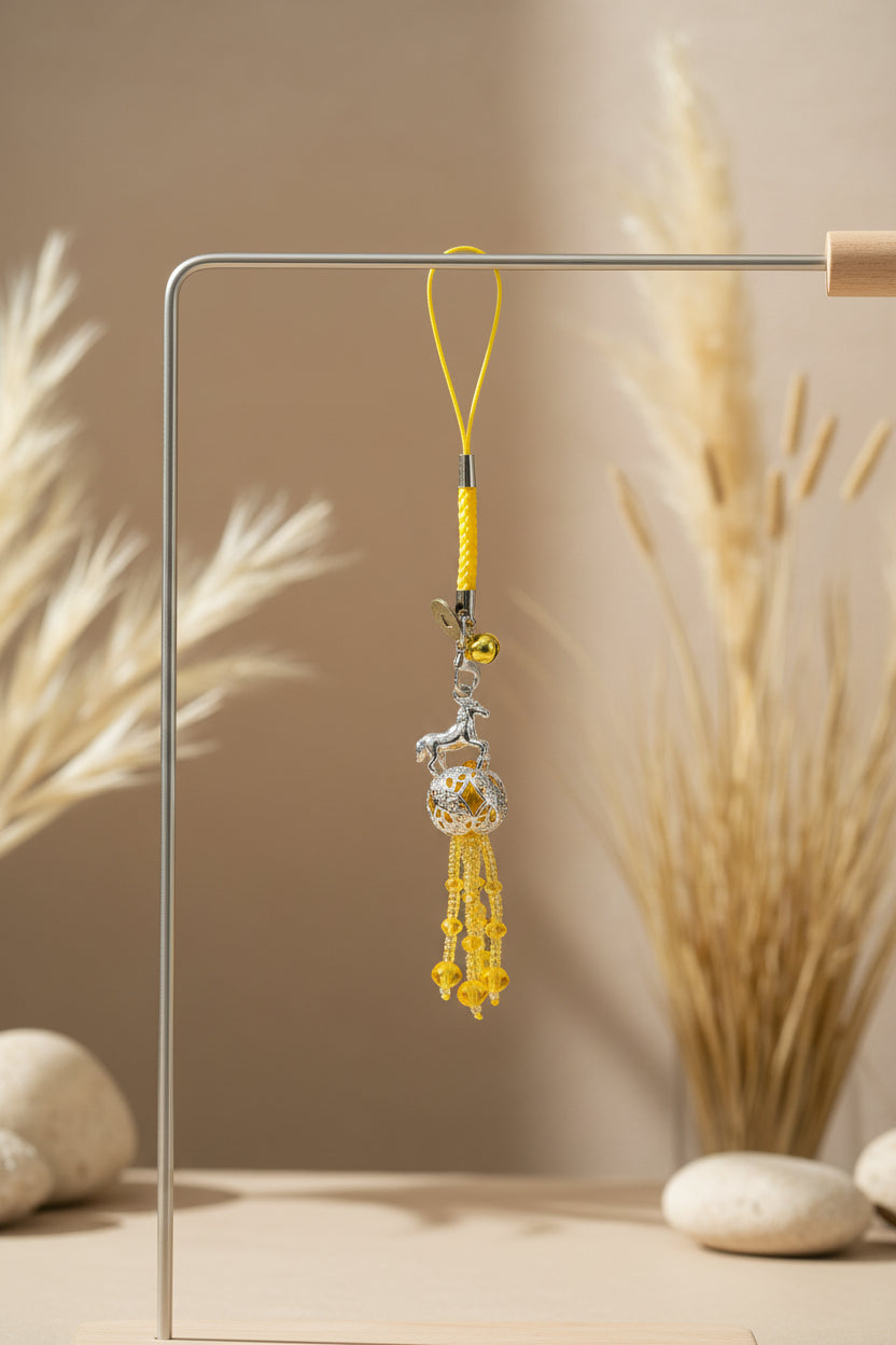 Decorative phone charm with yellow beads and silver accents on a white background