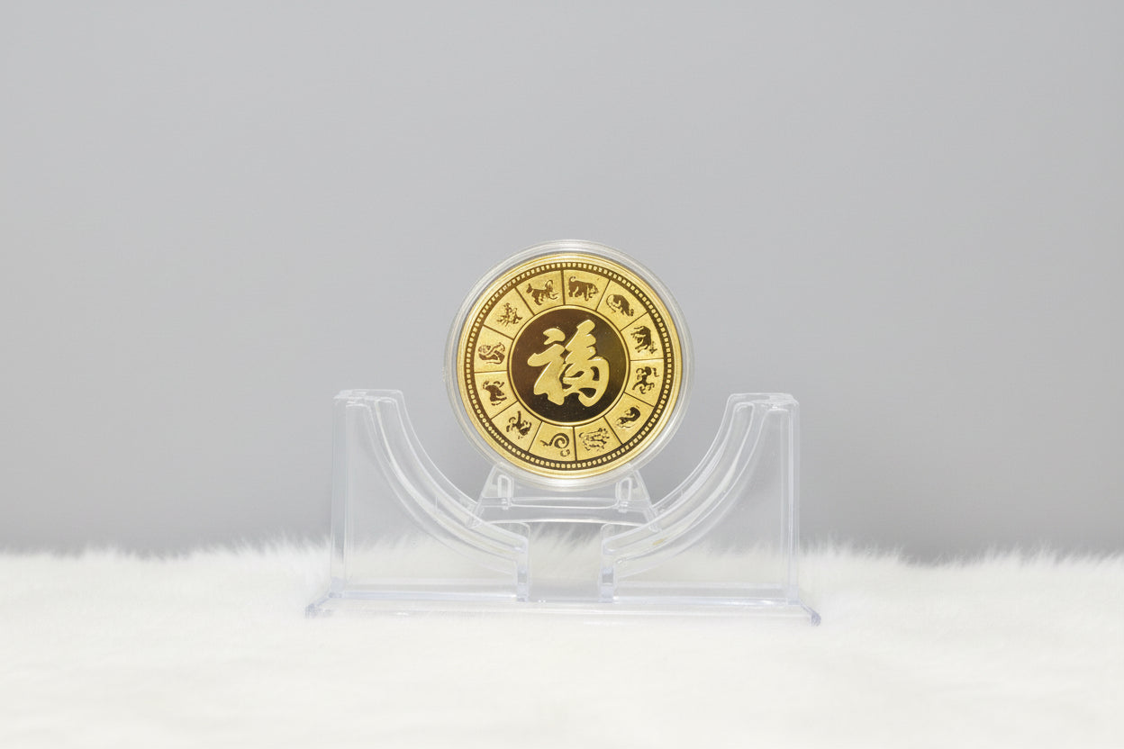 Gold coin with Chinese characters on a clear stand against a dark background